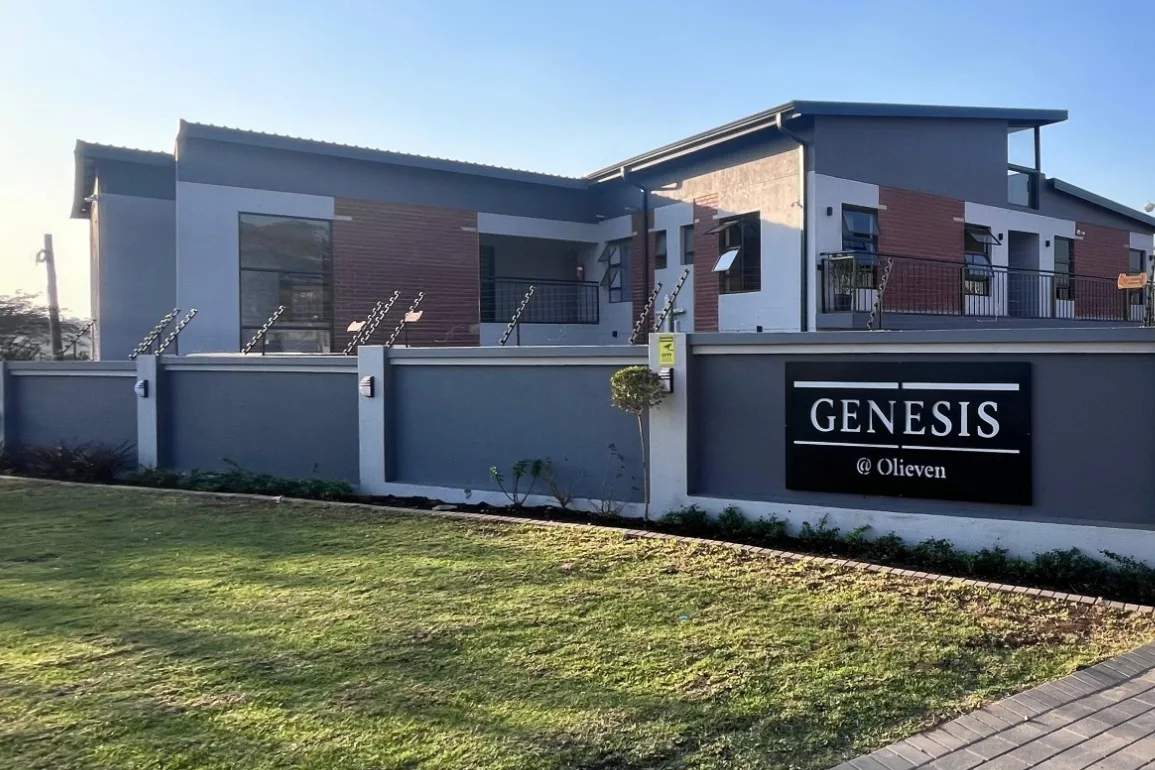 Genesis @ Olieven, a new 16-unit apartment building behind a grey boundary wall with its name sign