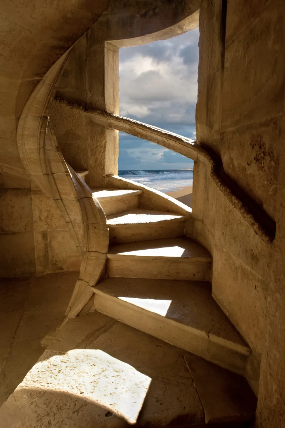 A stone spiral stair opening onto a window over the sea